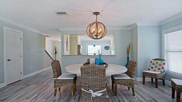 A dining area with wicker chairs, a round table, and a chandelier. - Luxury at the Beach, Totally Remodeled with Ocean Views Sea Place 12214! (St. Augustine)