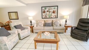 A living room with a sofa set, a coffee table, a chair, and a painting on the wall.
