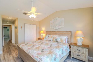 Ein Schlafzimmer mit einem Bett, zwei Nachttischen, einem Deckenventilator und einer Tür.