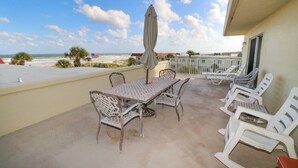 Een balkon met een tafel en stoelen, een uitzicht op het strand, en een Amerikaanse vlag.