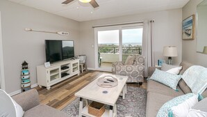 Un salon avec un téléviseur, un canapé et un balcon offrant une vue agréable.