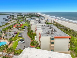A coastal hotel with a swimming pool, parking, and a view of the beach and ocean.