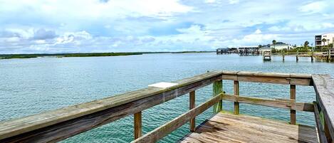 A wooden pier extending into a calm body of water with a clear sky above.
