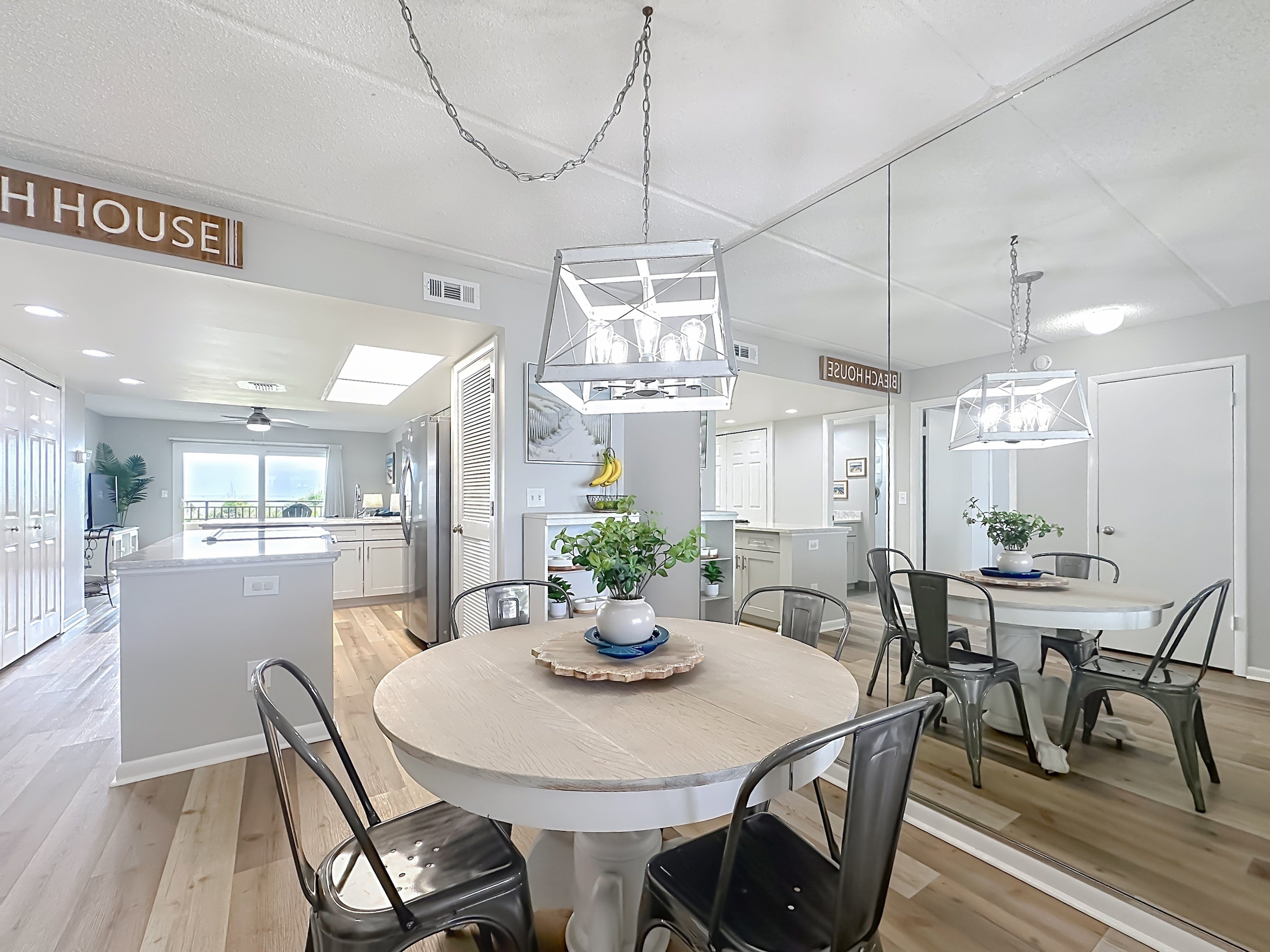 A modern kitchen with a central island, a dining area with a round table and chairs, and a view of the outside.