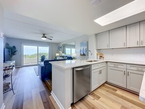 A modern kitchen with a central island, a dining area with a view, and a ceiling fan.