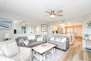 A modern living room with a grey sofa, a coffee table, and a ceiling fan.