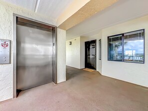 Un pasillo con una puerta, un interruptor de luz y una ventana con persianas.