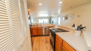 A kitchen with wooden cabinets, a stainless steel dishwasher, a gas stove, and a white countertop. - Windjammer 212 - Direct Oceanfront, Intracoastal Waterway Views in Crescent Beach (St. Augustine)