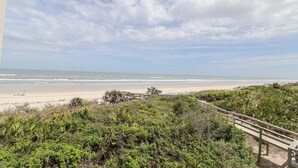 A beach view with a wooden walkway, sandy beach, and ocean. - Windjammer 212 - Direct Oceanfront, Intracoastal Waterway Views in Crescent Beach (St. Augustine)