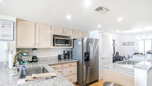Una cucina moderna con mobili chiari, un frigorifero in acciaio inossidabile, un forno a microonde e una macchina da caffè.