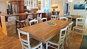 A spacious kitchen with a central island, white chairs, and a dining table. - Windjammer 312 - Remodeled, Direct Oceanfront Three Bedroom Crescent Beach Condo (St. Augustine)