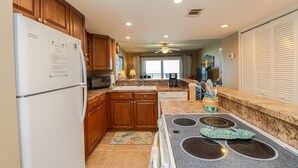 A modern kitchen with wooden cabinets, a refrigerator, a microwave, a stove, and a sink.