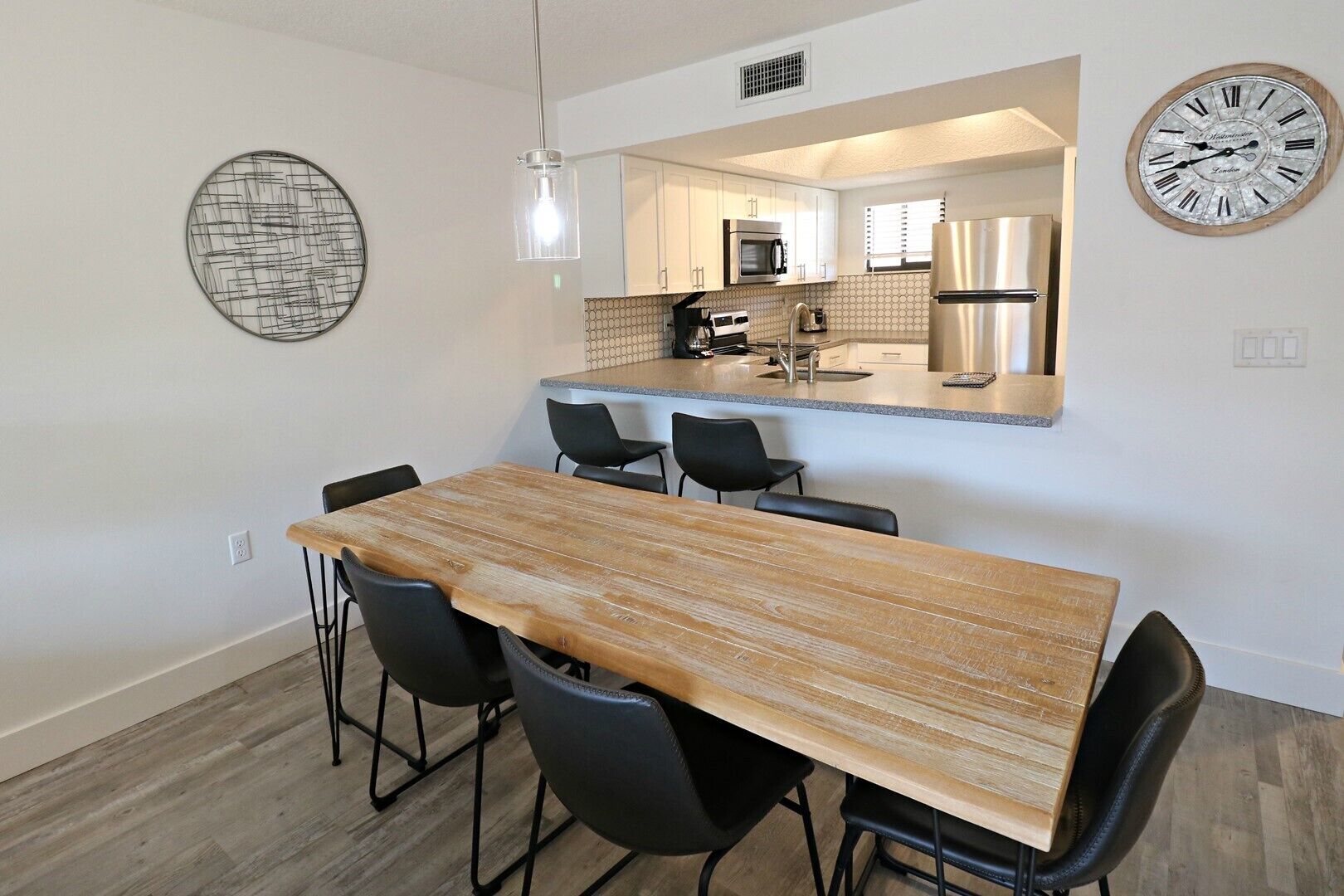 A modern kitchen with white cabinets, a stainless steel refrigerator, and a microwave.