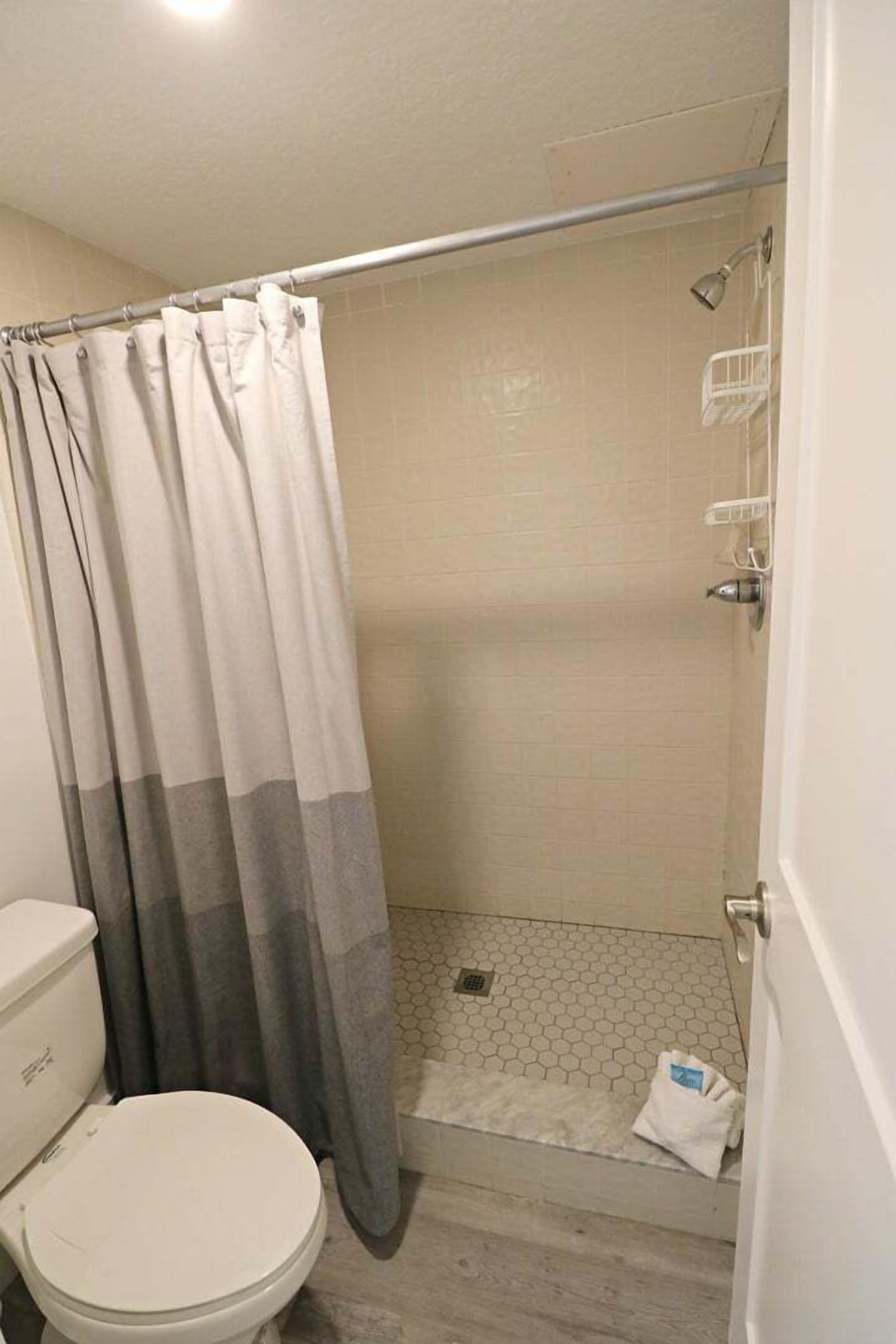 Un baño con ducha, inodoro y toallero.