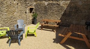 A courtyard with stone walls, a wooden table, and chairs.