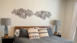 Ein Schlafzimmer mit einem Bett, zwei Nachttischen, zwei Lampen und einem Wanddekor.