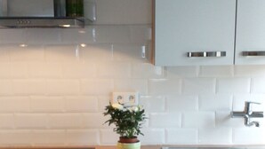 Eine moderne Küche mit weißen Schränken, einer Holz Arbeitsplatte, einem Spülbecken und einem kleinen Topf mit Pflanze.