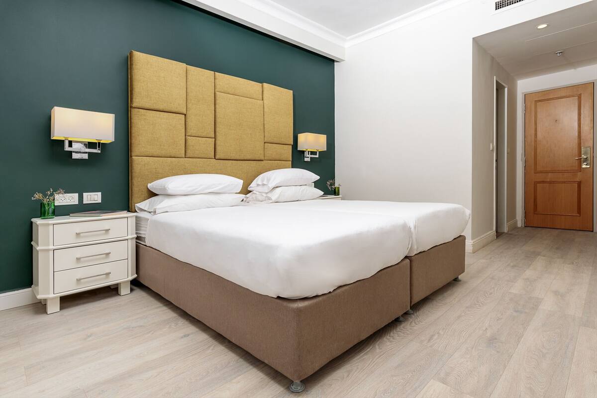 Une chambre d’hôtel moderne avec un grand lit, une table de chevet et une petite table d’appoint.