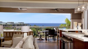 Een ruim balkon met uitzicht op zee, voorzien van een bank, stoelen en een eethoek.