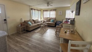 A living room with two sofas, a dining table, and a ceiling fan.