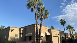 A building with a beige facade, multiple palm trees, and awnings over windows. - 2 Blocks from Carefree, AZ Town Center, Quiet and With Pool! (Carefree)