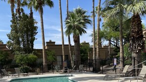 A swimming pool with clear water, surrounded by palm trees and lounge chairs. - Desert Escape With Pool! (Carefree)