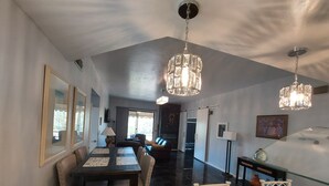 A spacious dining area with a high ceiling, modern chandeliers, and a view to the living room. - Desert Escape With Pool! (Carefree)