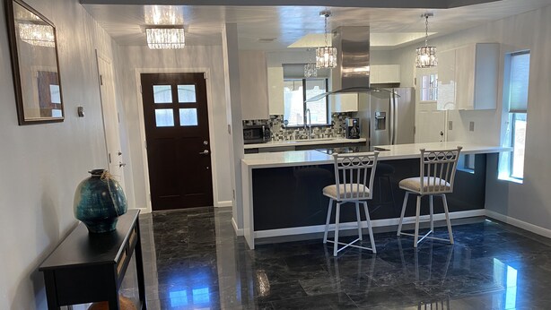 A modern kitchen with a central island, bar stools, and pendant lighting. - Desert Escape With Pool! (Carefree)