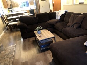 A living room with a sectional sofa, a coffee table with a plant, and a television in the background. - Yosemite! Bass Lake! Come Home to a Vaca!  (Bass Lake)