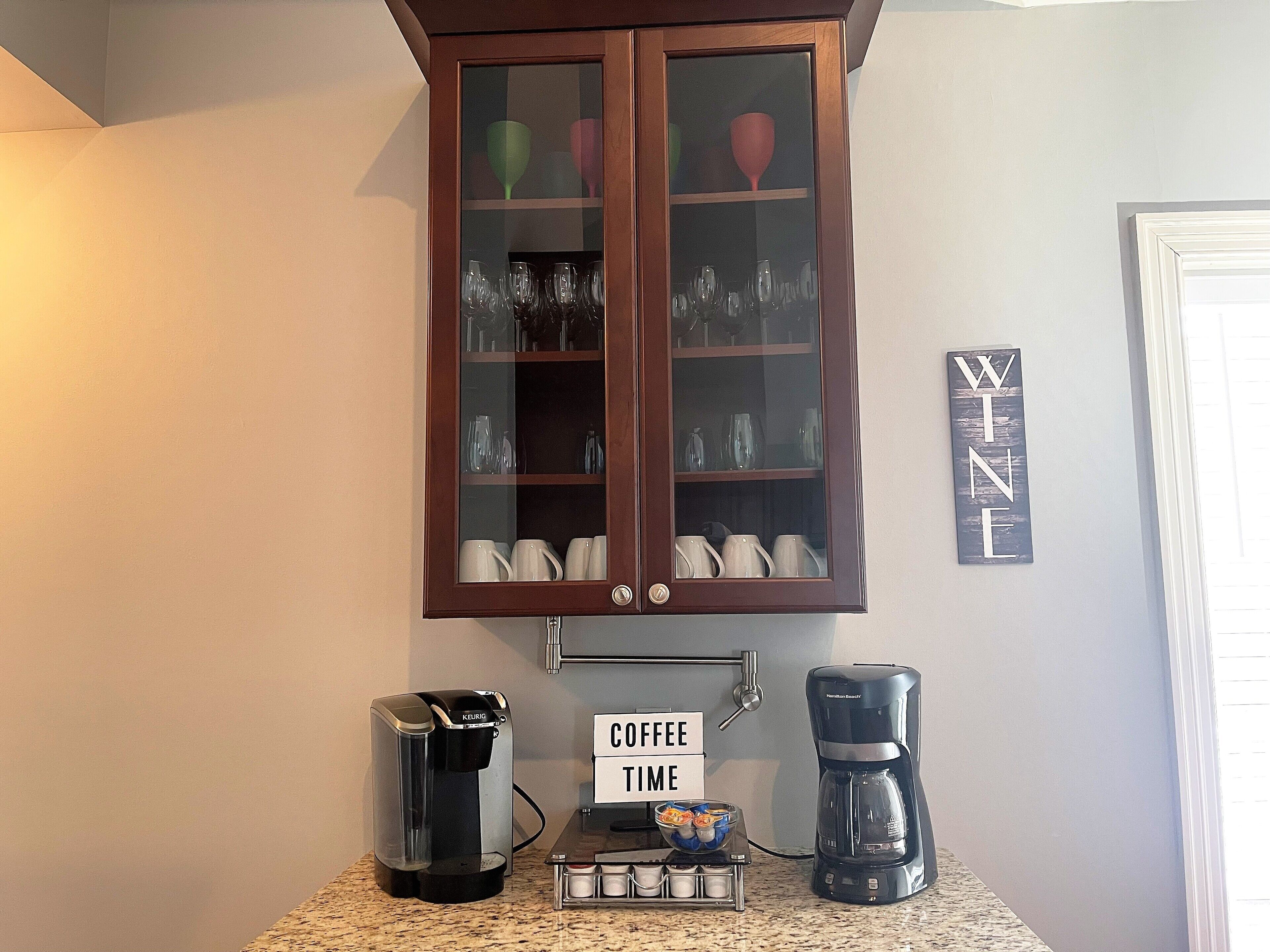 Ein Küchenbereich mit einer Kaffeestation, einem Schrank mit Glastüren und einem Schild mit der Aufschrift 'COFFEE TIME'.