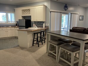 A kitchen with white cabinets, a central island with stools, and a refrigerator.