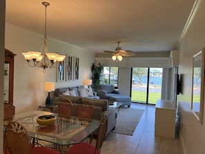 Relax in this spacious living area with a large dining table, comfortable sofa, and a TV mounted on the wall.