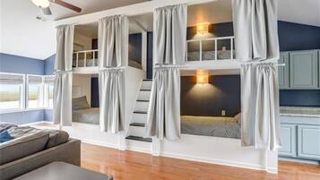 Habitación con literas de varios niveles, una escalera, ventilador de techo y vistas al exterior.
