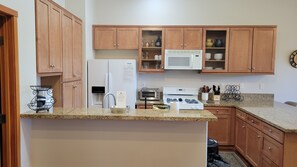 A kitchen with wooden cabinets, a refrigerator, a microwave, a toaster, and a stove.
