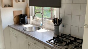 A modern kitchen with white cabinets, a granite countertop, a stainless steel sink, a gas stove, and a window providing natural light.