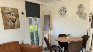 A modern living room with a brown sofa, a wooden coffee table with a plant, and a dining area with a round table and chairs.