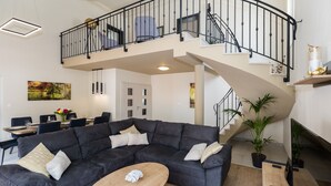 A spacious living area with a large sectional sofa, a wooden coffee table, and a staircase leading to an upper level. - Vitality Villa Mariante - free kayaks, private sauna (Komolac)