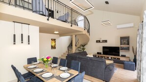 A modern living room with a dining area, a staircase, and a flat-screen TV. - Vitality Villa Mariante - free kayaks, private sauna (Komolac)