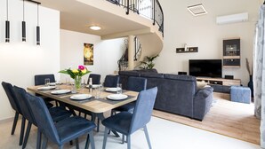 A modern living room with a dining area, a staircase, and a flat-screen TV. - Vitality Villa Mariante - free kayaks, private sauna (Komolac)
