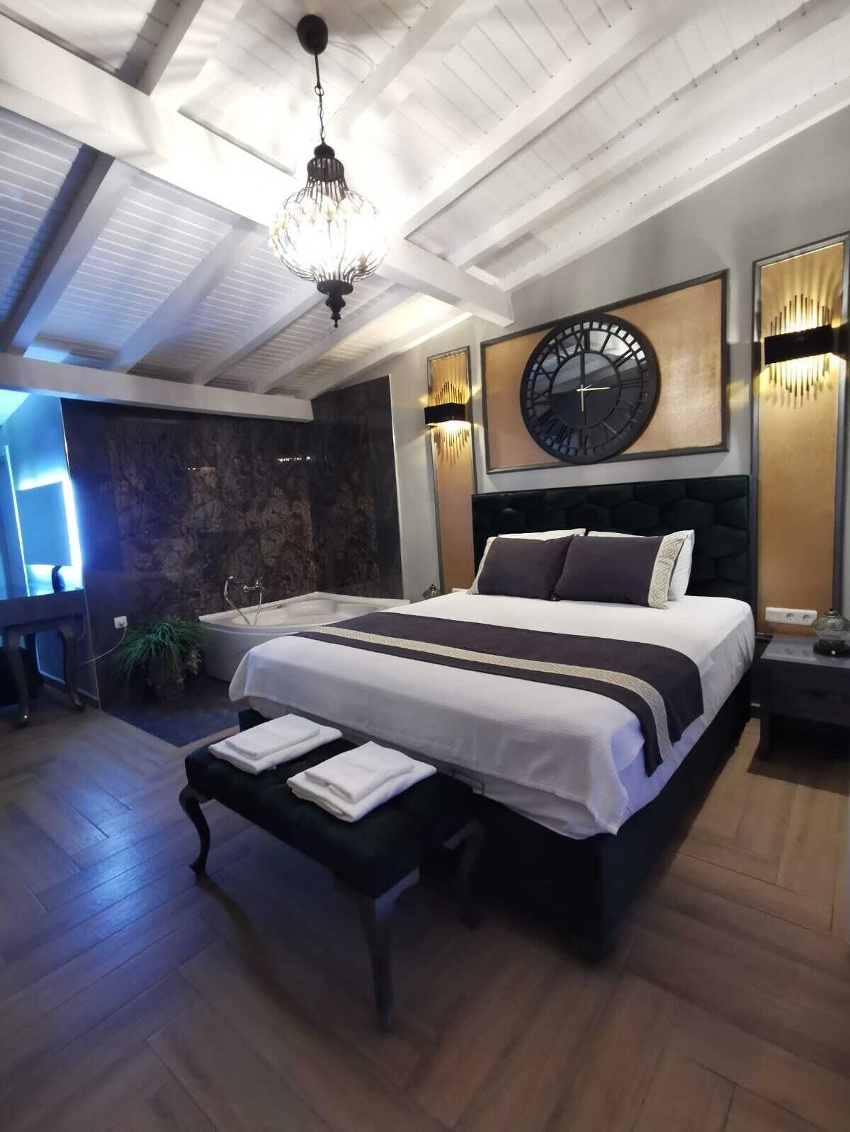 A modern bedroom with a large bed, a wall clock, and a chandelier.