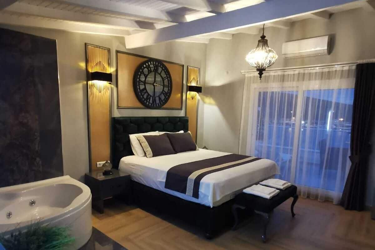 Un dormitorio moderno con una cama grande, una mesita de noche, una bañera y un ventanal con cortinas.