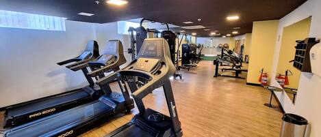 Een sportschool met loopbanden, krachtherinneringen en een houten vloer.