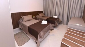 A hotel room with two beds, a sofa, a small table, and a curtain.