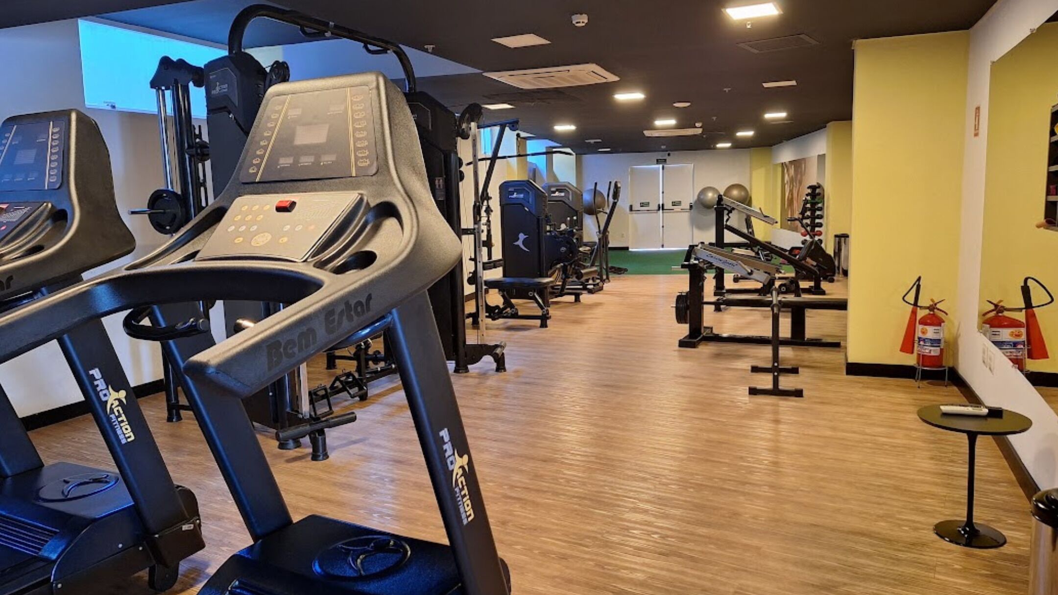 Un gimnasio con cintas de correr, máquinas de pesas y pelotas de ejercicio.