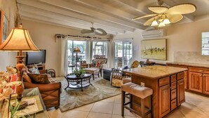 A spacious living area with a large island, comfortable seating, and a television. - Canal View Summer Escape With Dock, Hot Tub and Cabana Club Access (Key Colony Beach, Marathon)