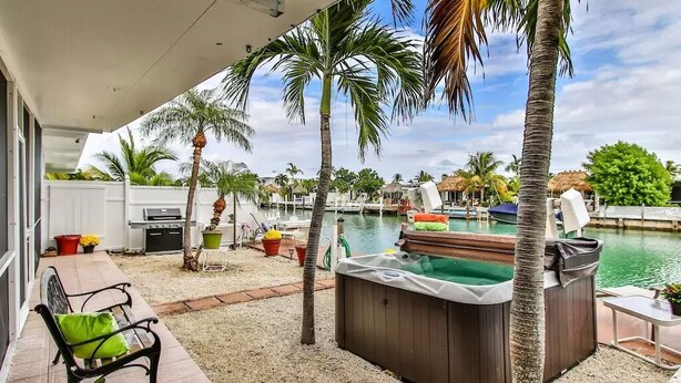 A patio area with a hot tub, a pool, and a grill. - Canal View Summer Escape With Dock, Hot Tub and Cabana Club Access (Key Colony Beach, Marathon)