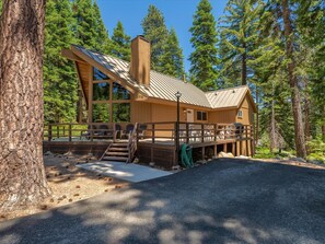 A lodge with a deck, outdoor seating, and a large window overlooking the forest. - Rim Drive Lookout (Tahoe Vista)