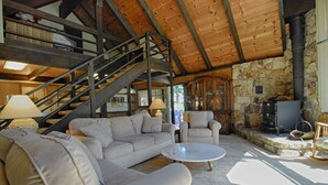 A spacious living area with a high wooden ceiling, a stone fireplace, a sofa, armchairs, and a coffee table. - Rim Drive Lookout (Tahoe Vista)