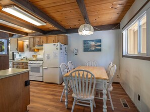 A kitchen with wooden cabinets, a refrigerator, a stove, and a dining table with chairs. - Rim Drive Lookout (Tahoe Vista)