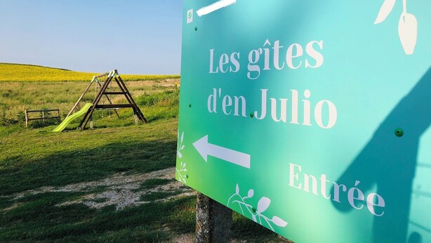 A sign with the text "les gîtes d'en Julio" and an arrow pointing left, indicating an entrance direction.